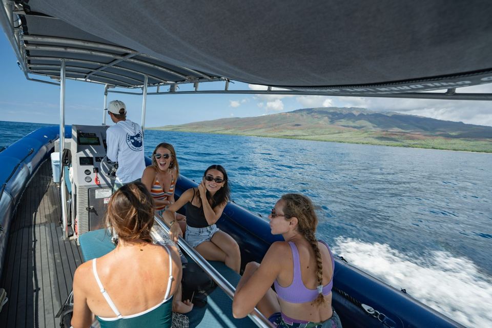 Guests seated along the raft as it runs the coast, West Maui behind